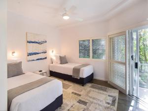 two beds in a room with two windows at Allambi in Noosa Heads
