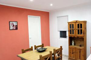 a dining room with orange walls and a wooden table at Departamento Monte Hermoso in Monte Hermoso