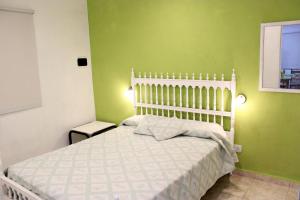 1 dormitorio con cama blanca y paredes verdes en Departamento Monte Hermoso en Monte Hermoso