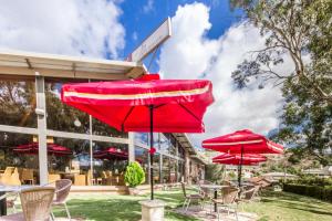 a group of tables and chairs with red umbrellas at Mannum Motel in Mannum