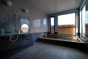 a bathroom with a tub and a shower and a window at とびた荘 #小学生以下は宿泊不可# in Oarai