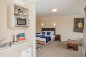 a bedroom with a bed and a kitchen with a sink at Finns Paekakariki in Paekakariki