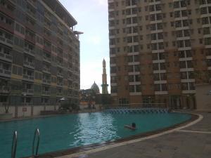 una persona en una piscina entre dos edificios en DSR Apartment Margonda Residence 2, en Depok