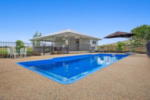 a blue swimming pool in front of a house at Casa Nostra Motel in Rockhampton