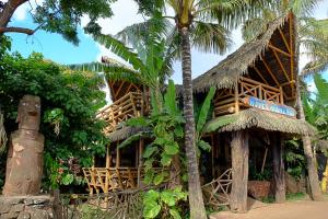 casa atropical com um telhado de palha e uma palmeira em Hotel Manavai em Hanga Roa