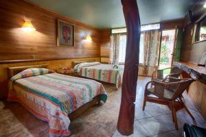 a bedroom with two beds and a desk and a chair at Hotel Manavai in Hanga Roa