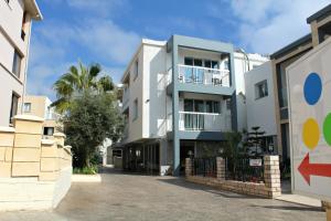 a white building with a palm tree in front of it at Maria Zintili Apartments in Ayia Napa