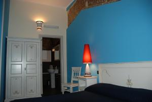 a blue bedroom with a bed and a red lamp at Locanda Re Ruggero in Monreale