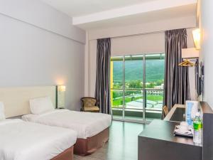 a hotel room with two beds and a desk and a window at MH Sentral Hotel Sg Siput in Ipoh
