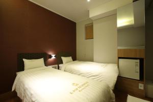 2 camas en una habitación de hotel con sábanas blancas en K-POP Residence Myeongdong 1, en Seúl