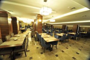Grand Cenas Hotel في أغري: غرفة طعام مع طاولات وكراسي خشبية