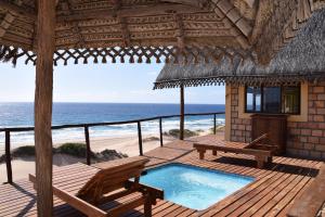 a resort with a pool and a deck with a view of the ocean at Khumbula iMozambique in Inhambane