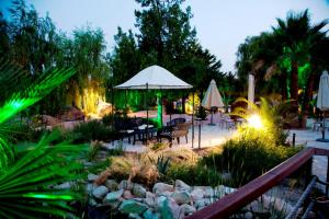a garden with tables and chairs and an umbrella at Jardines de Casablanca in Caravaca de la Cruz