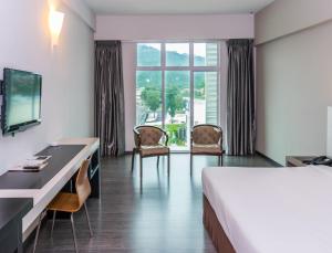 a hotel room with a bed and a desk and chairs at MH Sentral Hotel Sg Siput in Ipoh