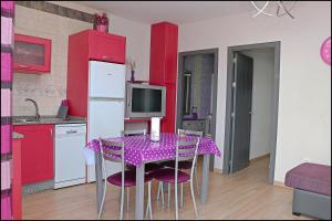 コニル・デ・ラ・フロンテーラにあるApartamento cerca Playa Batelesのキッチン(テーブル、紫色の椅子、赤いキャビネット付)