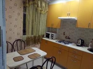 ペトロザヴォーツクにあるApartment on naberezhnaya La-Roshel 13のキッチン(黄色のキャビネット、テーブル、椅子付)