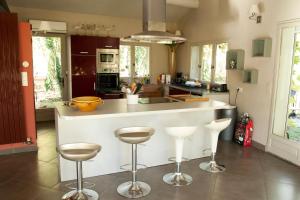a kitchen with a white counter and stools in it at Domaine des Petits Cancets in L'Isle-sur-la-Sorgue