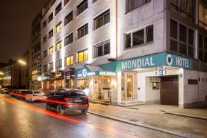ein Auto, das nachts vor einem Gebäude parkt in der Unterkunft Centro Hotel Mondial in München