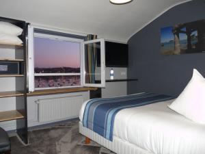 a bedroom with a bed and a window with a view at Hôtel des Rochers in Perros-Guirec