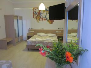 a bedroom with a bed and a mirror and flowers at Hippocampus Hotel in Kamari