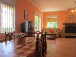 sala de estar con paredes de color naranja, TV y sofá en Casa Rural Las Duronas, en Almagro
