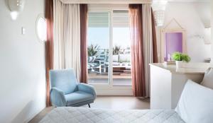 a bedroom with a bed and a chair and a balcony at Hotel LaMorosa in Rimini