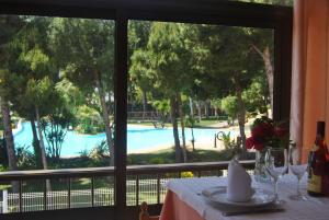 a table with a view of a pool through a window at Hotel Sancho III in Alcossebre