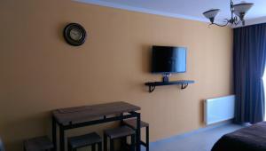 Habitación con mesa y TV en la pared. en Valley Bakuriani, apartment 303, en Bakuriani