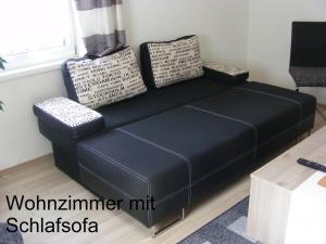 Sofá negro en una sala de estar con ventana en Ferienwohnung Huber, en Dornbirn
