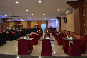 a dining room with tables and red chairs at Puncak Budget Hotel in Pangkal Pinang