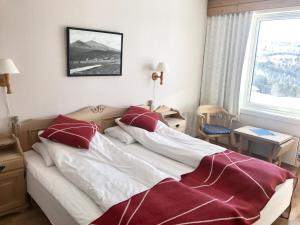 a bedroom with a bed with red and white sheets and a window at Øigardseter Fjellstue in Høvringen