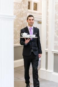 a man in a suit holding a tray of food at Trout Hotel in Cockermouth