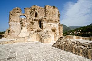 an old stone building on a hill with mountains in the background at Residenza d'Epoca Borgodifiume in Fiumefreddo Bruzio