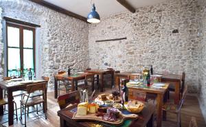 a restaurant with wooden tables and a stone wall at Residenza d'Epoca Borgodifiume in Fiumefreddo Bruzio