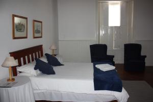 a bedroom with a bed with blue pillows and two chairs at Karoopark Guest House in Graaff-Reinet