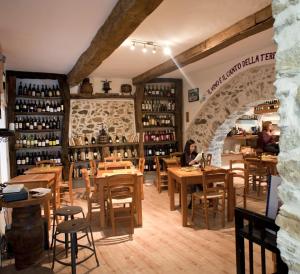 a restaurant with wooden tables and a stone wall at Residenza d'Epoca Borgodifiume in Fiumefreddo Bruzio