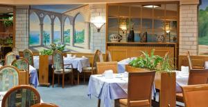 a restaurant with white tables and chairs and a painting at Hotel Rubin in Düsseldorf