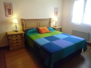 1 dormitorio con 1 cama colorida y 2 mesitas de noche en Apartamento Ajo, en Ajo
