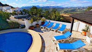 モライラにあるLa Madrugada - Luxury Moraira Villa With Sea Views and Private Heated Poolのパティオ(青い椅子付)、スイミングプール