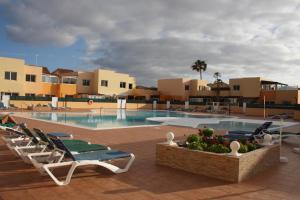 a swimming pool with lounge chairs in a resort at Anju Villas Los delfines Bravo's apartments in Corralejo