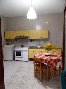 kuchnia z żółtymi szafkami i stołem z kwiatami w obiekcie Casa Relax Mare Trebisacce w mieście Trebisacce