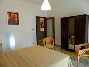 een slaapkamer met een bed en stoelen en een spiegel bij Casa Relax Mare Trebisacce in Trebisacce
