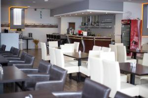 a restaurant with white chairs and tables and a bar at Hotel Slavie in Cheb