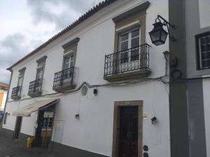 een wit gebouw met 2 balkons en een deur bij Avis Guesthouse in Évora