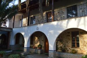 a white building with arches and a balcony at Casa Rural La Vallejera in Tejeda de Tiétar