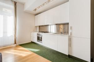 a kitchen with white cabinets and a green rug at Micol's Place in Rome