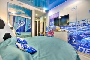 a bedroom with a bed with blue pillows and a tv at Alex Hotel on Bogatyrsky in Saint Petersburg