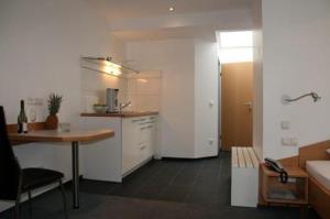ケルンにあるApartment-Hausの白いキャビネットとテーブル付きのキッチンが備わります。