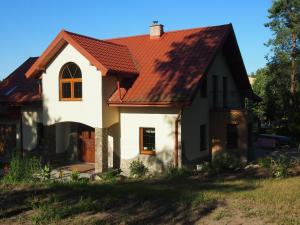 a white house with a red roof at Domek Leśna Przystań in Strękowizna