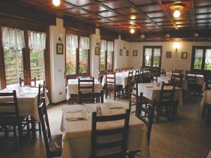 Albergo La Genzianella في بيلاجيو: غرفة طعام مع طاولات وكراسي ونوافذ